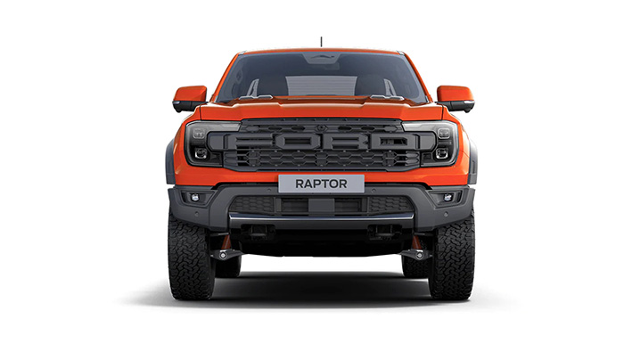 Vorderansicht eines orangefarbenen Ford Raptor mit markantem Kühlergrill und Offroad-Reifen.